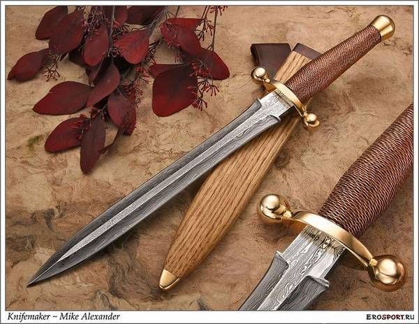 two knives sitting next to each other on top of a wooden table with red leaves