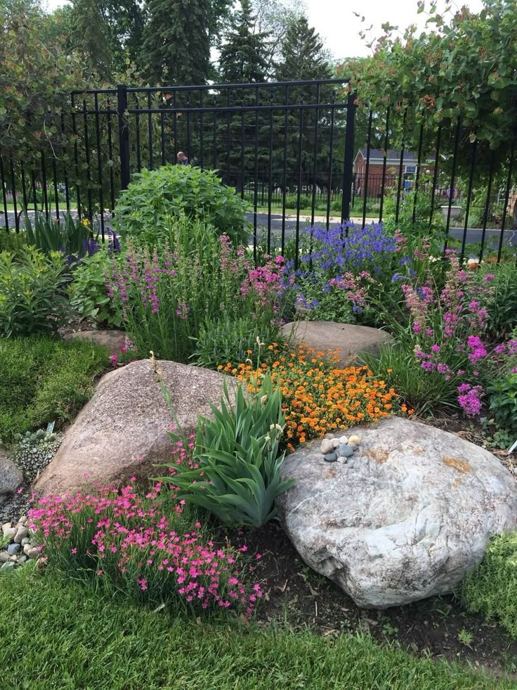 a garden with flowers and rocks in the grass