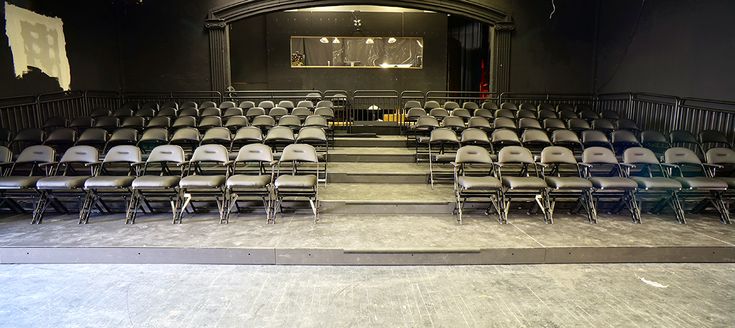 an empty auditorium with rows of chairs in front of the stage and on the floor