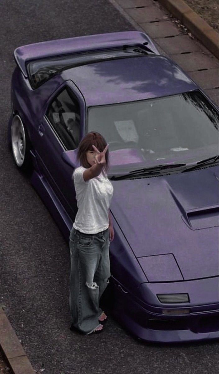 a woman leaning on the hood of a purple sports car