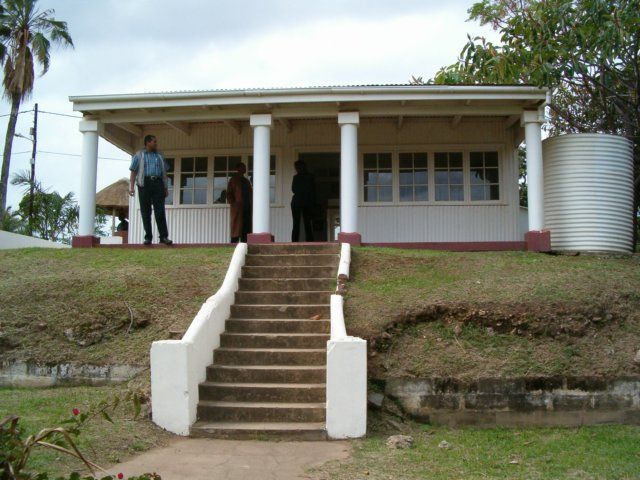 two people are standing on the steps leading up to a small white building with columns