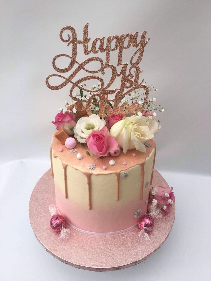 a pink and gold birthday cake with flowers on top