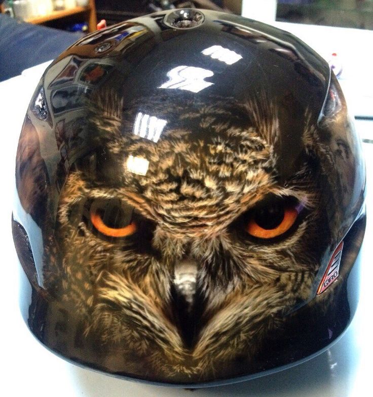 an owl's face is shown on the back of a motorcycle helmet with orange eyes