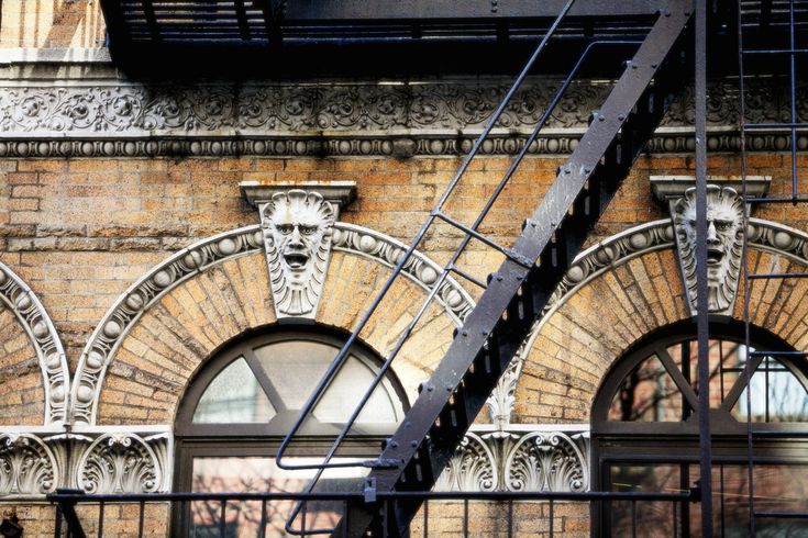 an old brick building with metal railings and stairs leading up to the entrance door