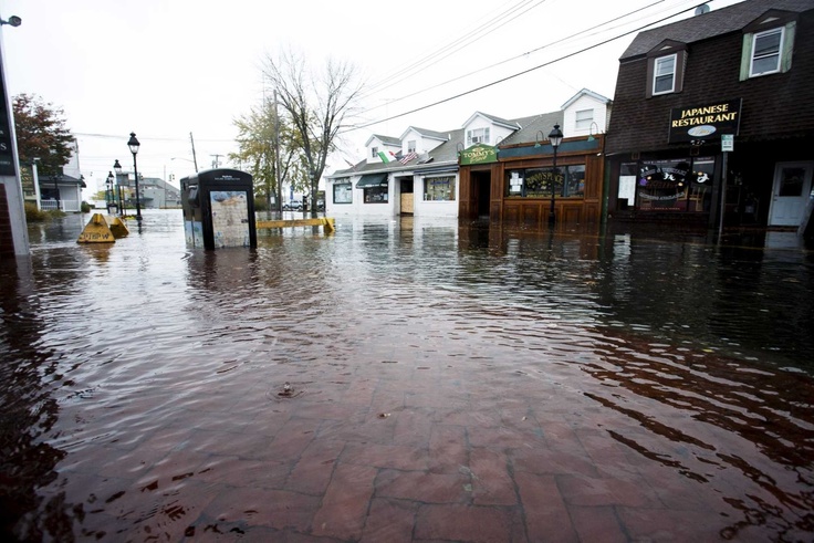 a flooded street in front of several buildings with signs on the side and water covering the sidewalk