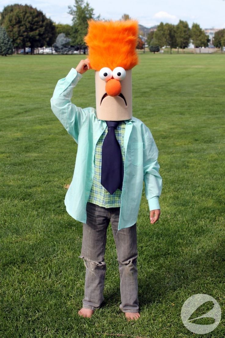 a young boy wearing an orange wig and tie standing on top of a lush green field