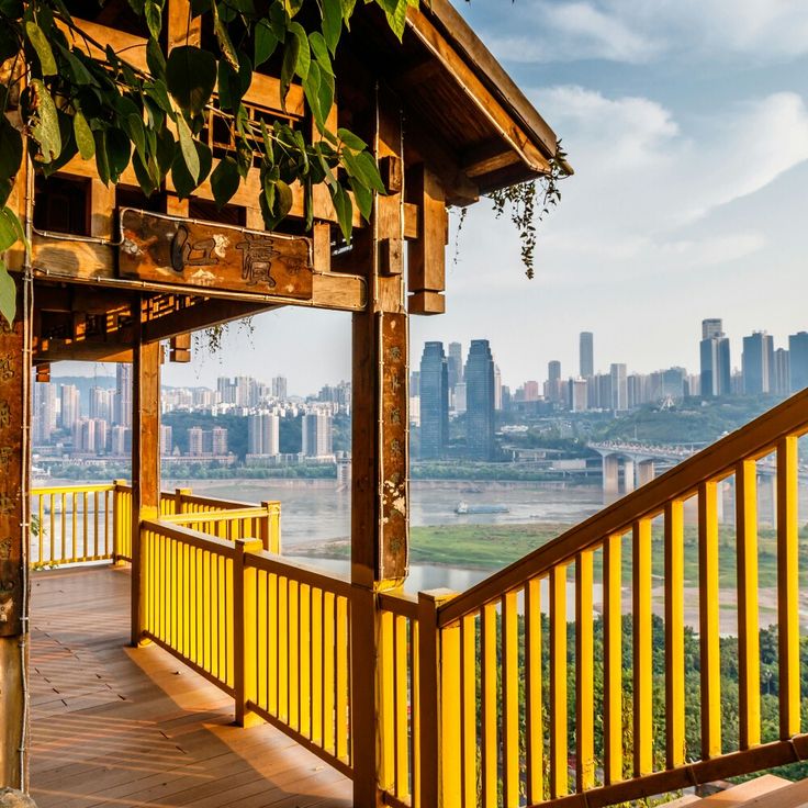 a wooden porch with yellow railing overlooking a city