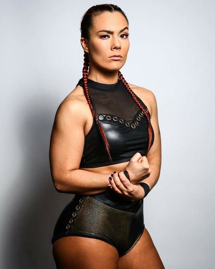 a woman with braids in her hair posing for the camera, wearing a leather outfit