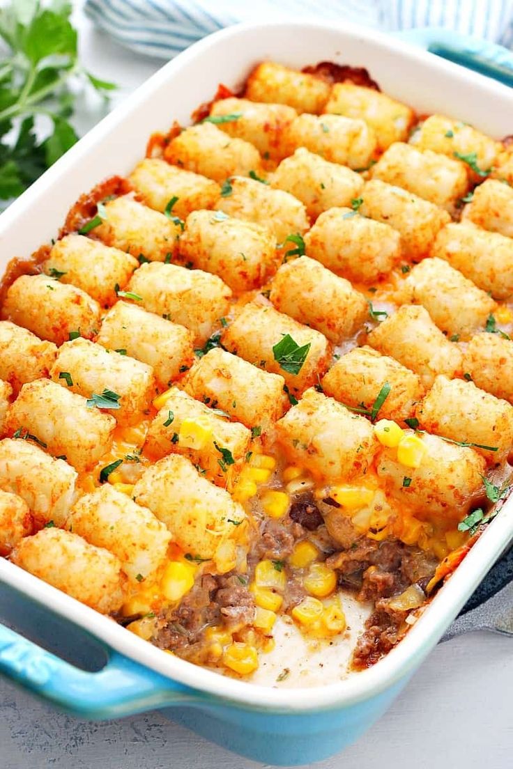 a casserole dish with tater tots and corn on the cob