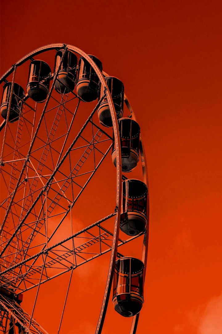 a ferris wheel against an orange sky with clouds