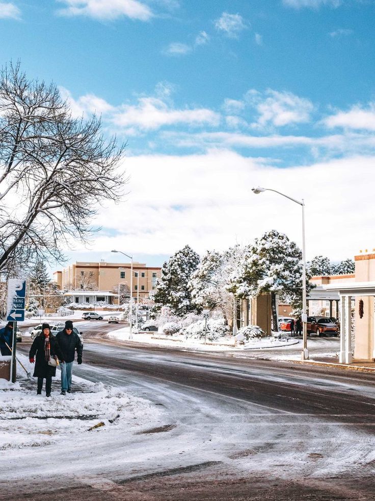 two people are walking down the street in the winter time with snow on the ground