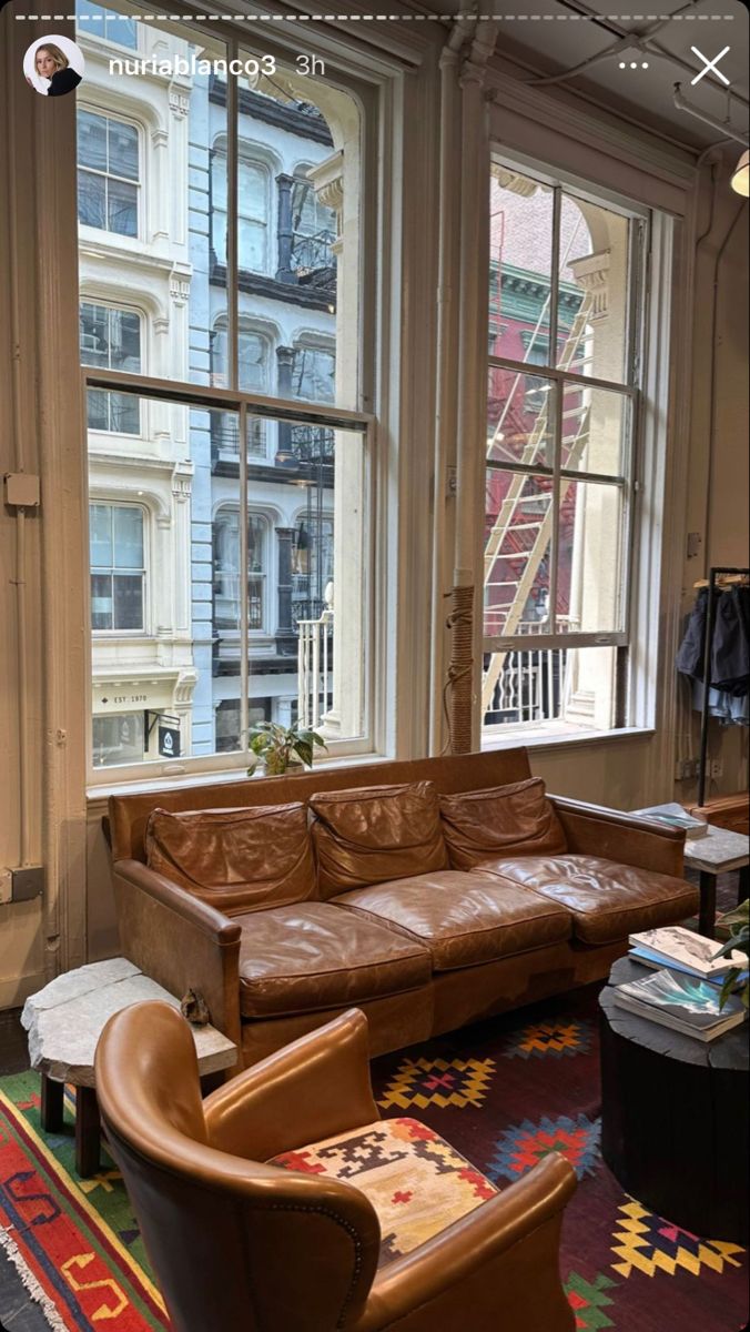 a living room filled with furniture next to large windows and a rug on the floor