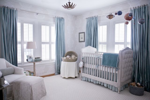 a baby's room with blue drapes and white furniture, including a crib