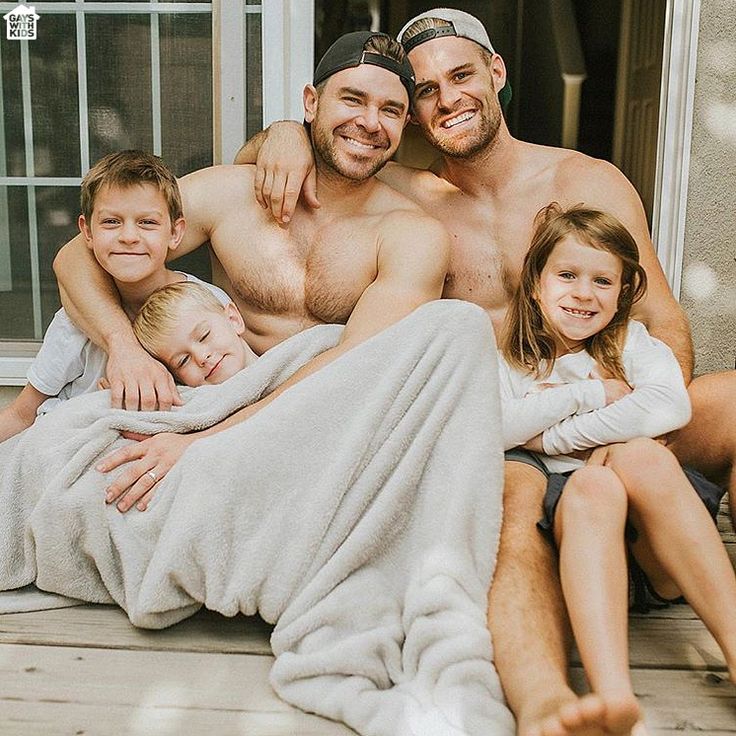 a man, woman and two children sitting on a porch with a blanket over them