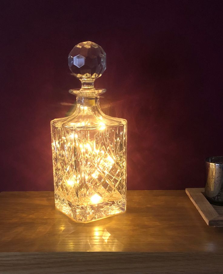 a lighted glass bottle sitting on top of a wooden table next to a candle holder