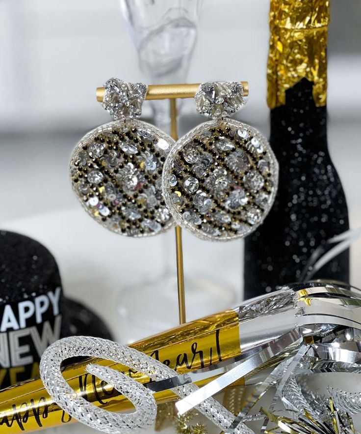 Introducing our "Ball Drop Earrings" in stunning silver – the perfect accessory to bring a touch of glamour to your New Year's Eve ensemble. These earrings feature a 2-tier design with new year's disco ball beaded embroidery, creating a dazzling and celebratory look.
Crafted with intricate details, including crystal rhinestones, sequins, seed beads, and beaded embroidery, these earrings capture the festive spirit of New Year's celebration. With a height of 2.75" and a width of 2", they make a bold statement, adding sparkle and elegance to your overall look.
Celebrate the countdown to the new year with style and sophistication by adorning these "Ball Drop Earrings" in silver. Handcrafted and handmade, these earrings are a unique and eye-catching addition to your festive wardrobe, ensu Party Jewelry With Bling, Metal Dangle Crystal Earrings For Party, Party Crystal Hoop Earrings, Glamorous Crystal Clip-on Earrings For Party, Glamorous Sparkling Clip-on Earrings For Gift, Metal Hoop Earrings For Parties, Rhinestone Hoop Earrings For Party, Metal Crystal Earrings For Party, Metal Crystal Earrings For Pierced Ears For Party