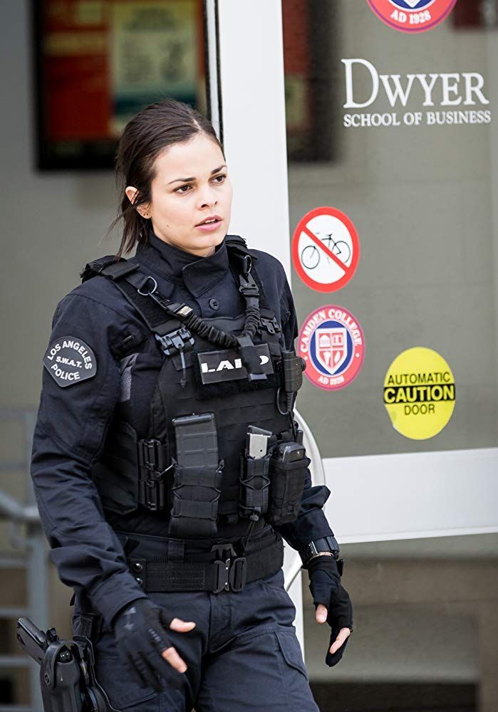 a female police officer standing in front of a building with her hand on her hip