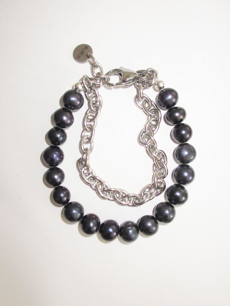 a bracelet with black pearls and silver chains on a white background, close up view