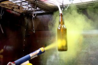 a beer bottle is being sprayed with yellow liquid