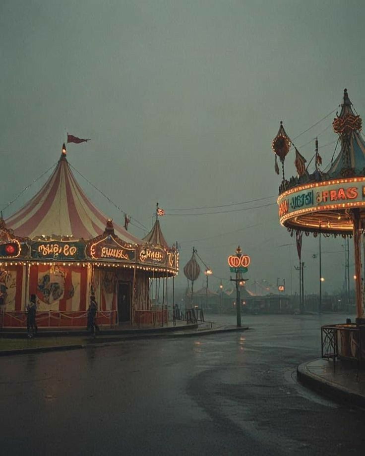 an amusement park at night with the lights on and people walking around in the rain