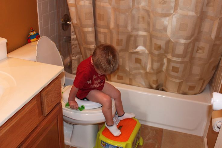 a little boy sitting on top of a toilet in a bathroom next to a sink