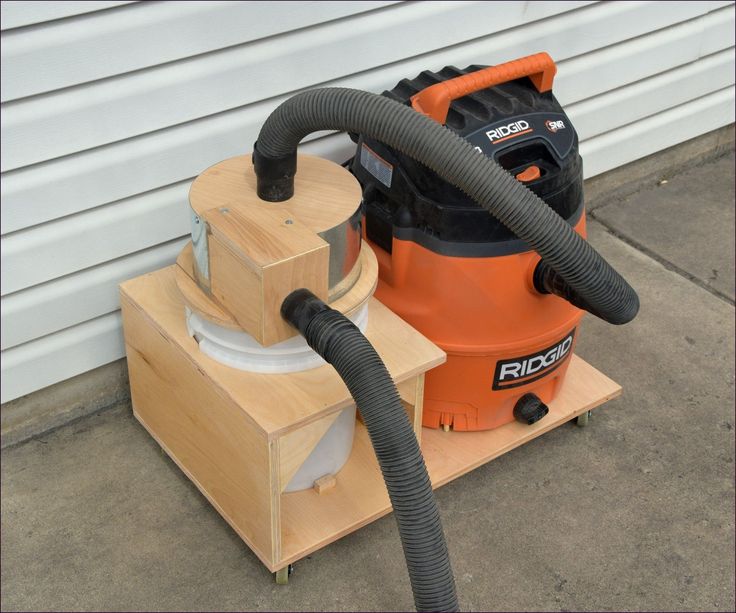 an orange and black vacuum sitting on top of a wooden block