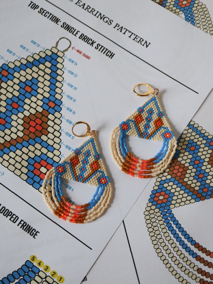 two pairs of beaded earrings sitting on top of a piece of paper next to each other