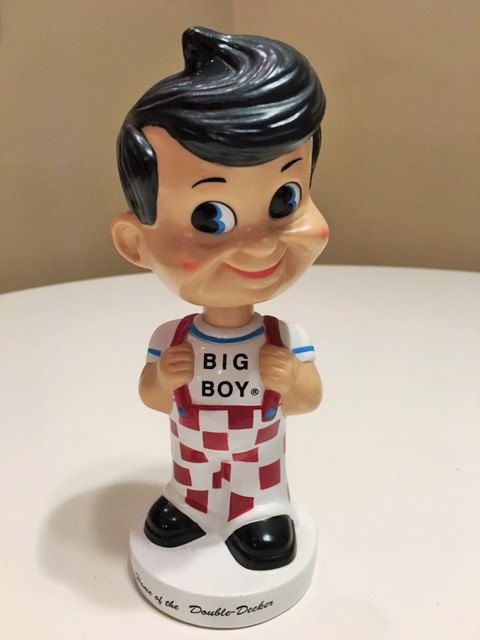 a small figurine is sitting on a white table with the words big boy