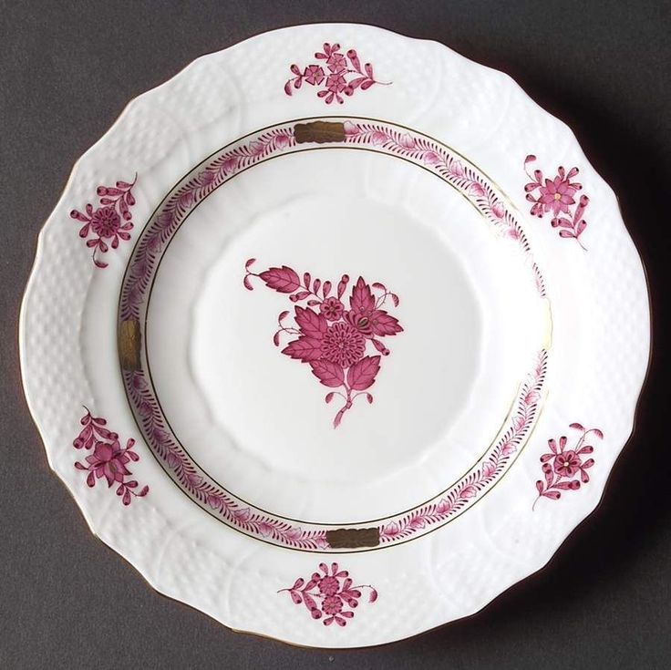 a pink and white plate with flowers on the rim is sitting on a gray surface