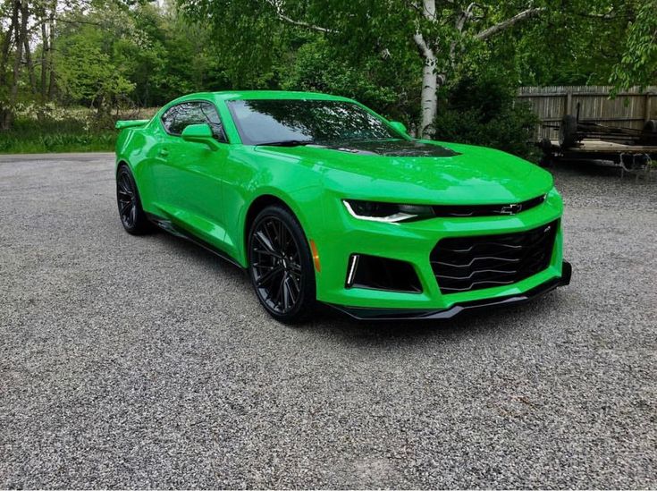 a bright green chevrolet camaro is parked in the parking lot next to some trees