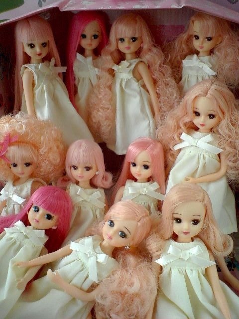 a bunch of dolls that are sitting in a box with pink hair and white dresses