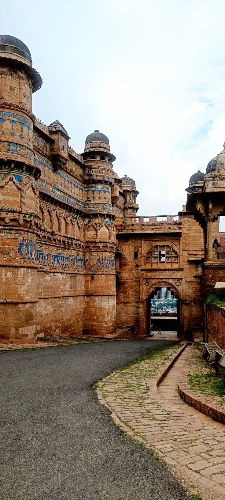 an old building with blue and gold designs on it's sides, next to a paved walkway