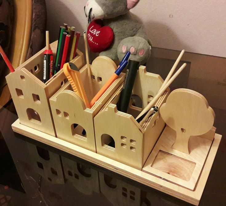 a teddy bear sitting on top of a desk next to a holder with pens and pencils