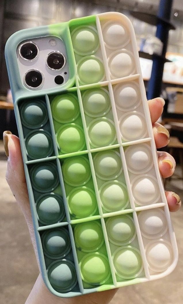 a person holding up a cell phone case with compartments filled with different colored eggs in it