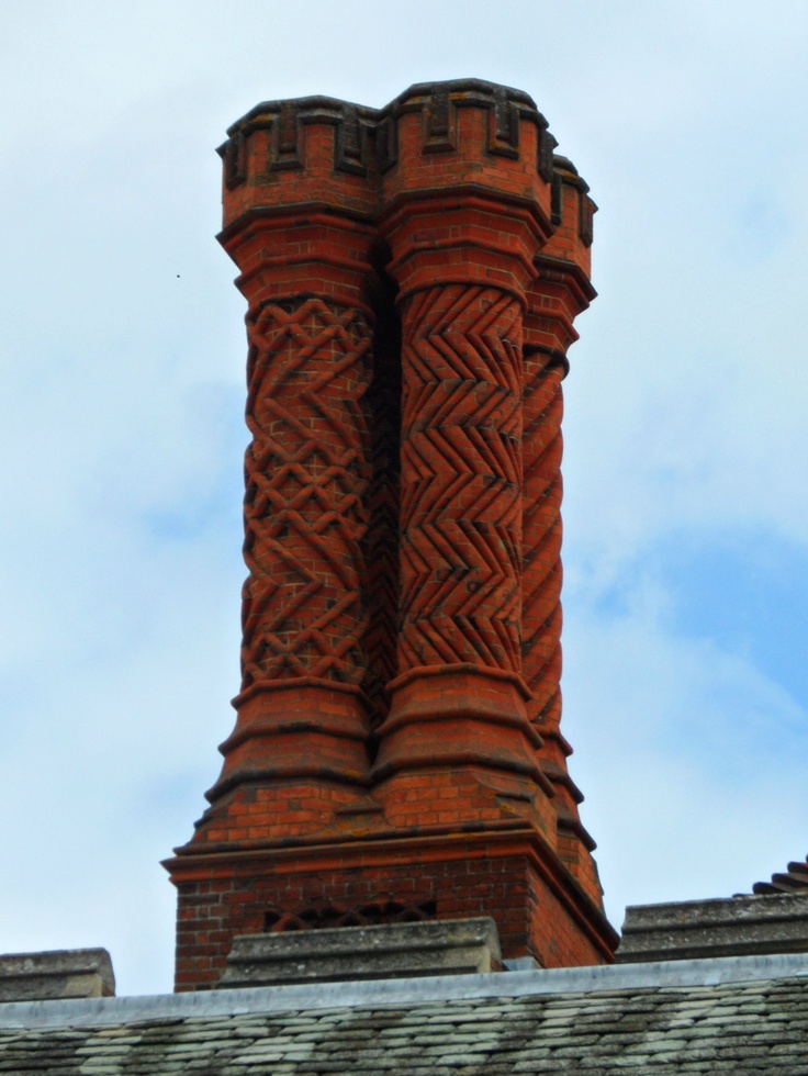 two tall brick towers on top of a building next to a blue sky with clouds in the background