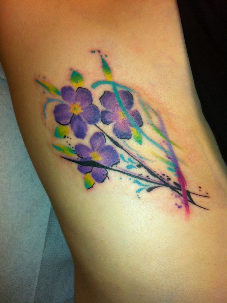 a woman's tattoo with purple flowers on her arm