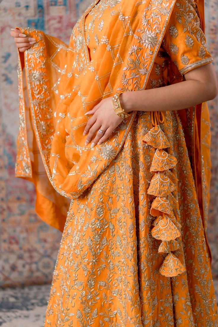 Channelize your desi vibes with adorable Apricot coloured Lehenga. A fashion-savvy lady who resides in our body will never compromise with our looks at any cost. Lehenga is always the perfect sartorial choice for all women when it comes to attending a wedding. Keeping in mind your style statement, we have designed this beautiful apricot-coloured lehenga for our pretty ladies. This lehenga is made from raw silk material and embroidered with zardozi, sequins, and dabka. It is the perfect attire fo Orange Cutdana Palazzo Set For Festivals, Orange Designer Palazzo Set For Navratri, Orange Palazzo Set With Dupatta And Traditional Drape, Semi-stitched Orange Palazzo Set With Gota Work, Traditional Drape Orange Palazzo Set With Dupatta, Semi-stitched Orange Palazzo Set With Zari Work, Designer Orange Palazzo Set With Zari Work, Orange Semi-stitched Palazzo Set For Navratri, Orange Palazzo Saree Set For Diwali