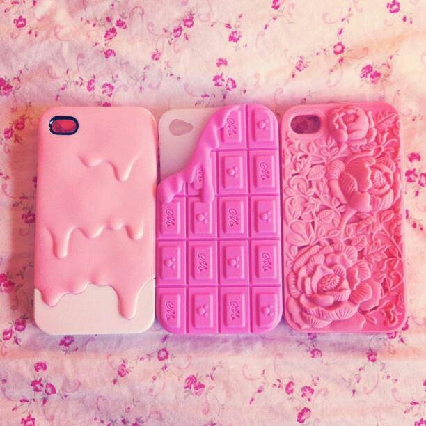 three cell phones are lined up next to each other on a pink surface with flowers