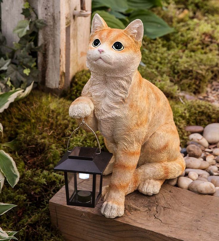 an orange and white cat statue sitting on top of a wooden block next to a light