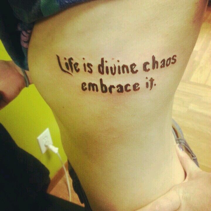 a woman with a tattoo saying life is divine chaos embrace it