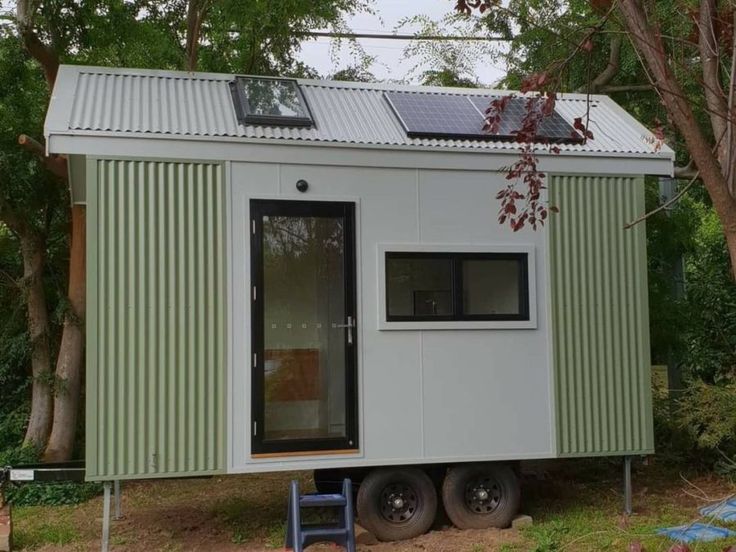 the tiny house is built on wheels and has a solar panel covering it's roof