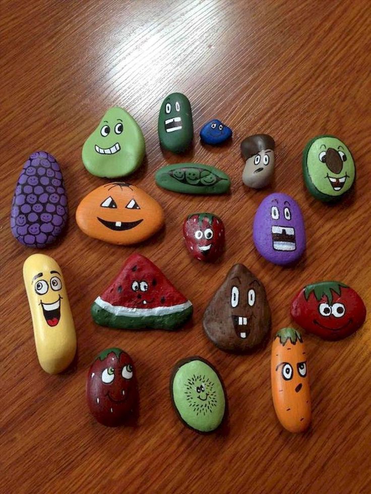 many different rocks with faces on them sitting on a wooden table next to each other