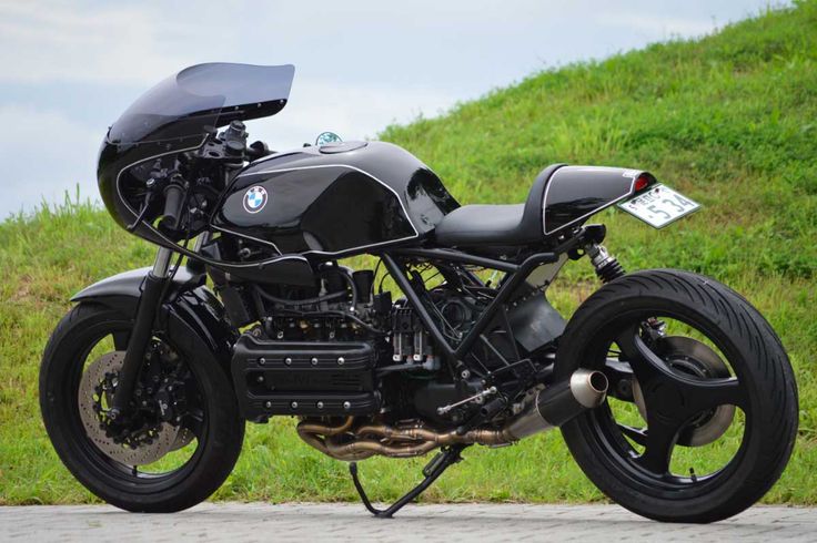 a black motorcycle parked on the side of a road next to a lush green hillside