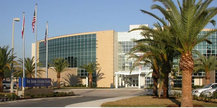 a large building with palm trees in front of it and cars parked on the street