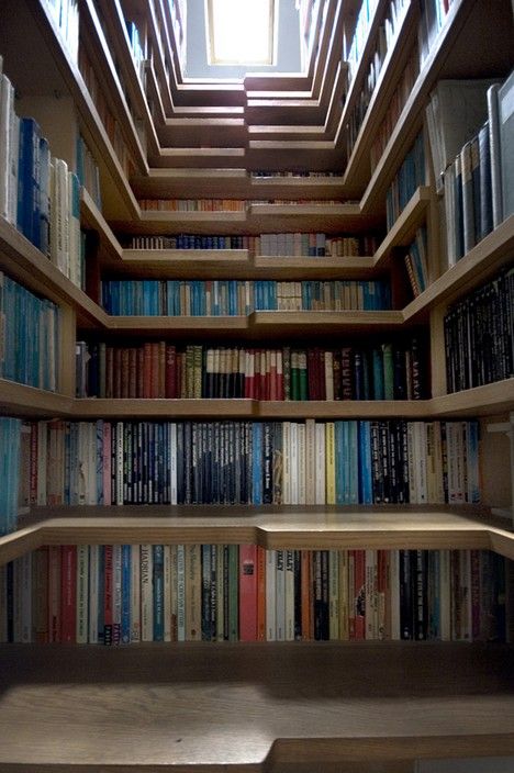 an empty bookshelf filled with lots of books under a skylight in a library