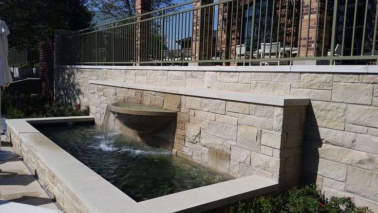 there is a water fountain in the middle of this patio area that has steps leading up to it