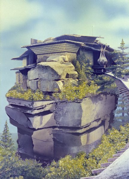 a house built into the side of a cliff with trees growing out of it's roof