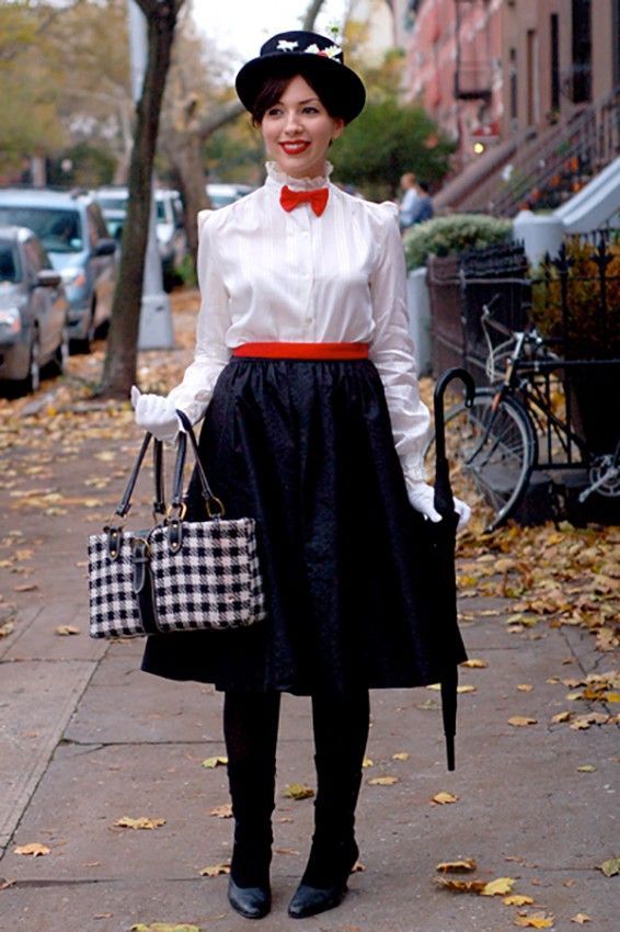 a woman is standing on the sidewalk holding a purse and smiling at the camera while wearing a bow tie