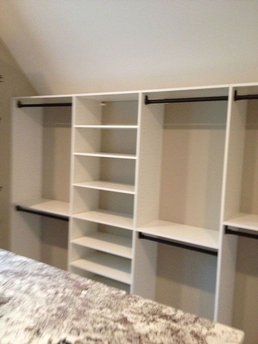 an empty bedroom with white shelves in it