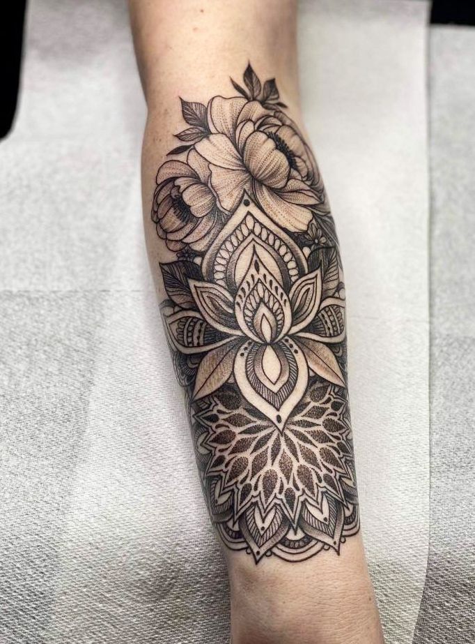 a woman's leg with a flower and lotus tattoo on the side of her arm